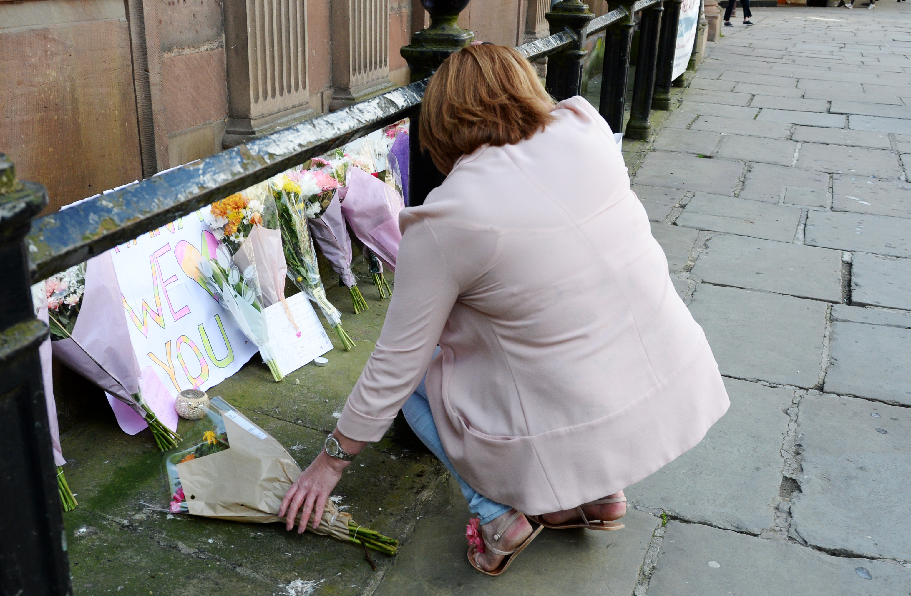 A woman leaves flowers outside St Ann's Church in Manchester