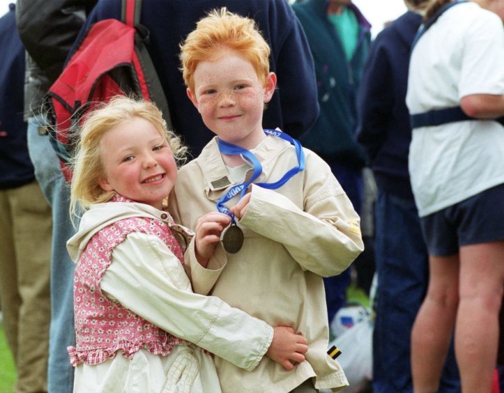 Seven-year-old Elloitt Griffiths  gets a cuddle from his sister Harriet,5, after running in the 1K race in 2000.