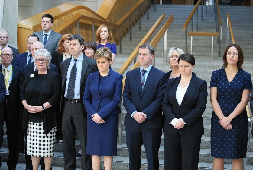 First Minister Nicola Sturgeon joins colleagues in observing a minute's silence in the Garden Lobby of the Scottish Parliament