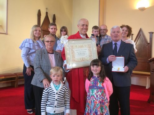 Tom Cairns with his wife and family, along with Father Mark Impson.