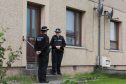 Two police officers stand guard outside a house at in Willowbank, Wick
