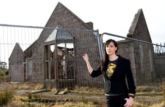 Resident Carrie Zeiler stands in front one of the derelict buildings on the site of Kingseat hospital.