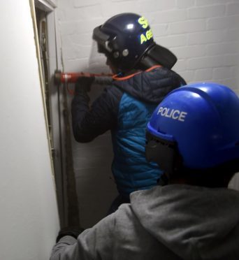 Officers ram through the door of the flat in Regent Court, Aberdeen.