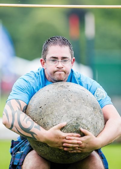 A competitor attempts to get the Inverness Stone over the bar at the Inverness Highland Games.