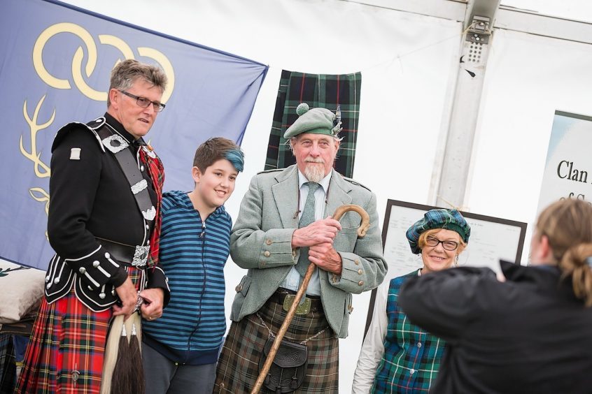 A young visitor poses with exhibitors at the Clan village at the Inverness Highland Games.