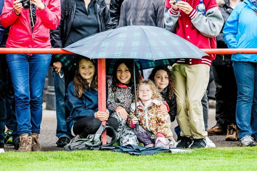 Young visitors take shelter to watch the events at the Inverness Highland Games.