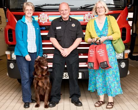 Left to right: Pheona Horne with Loki the dog, Lerwick station manager, Graham Reid and Tricia Brown holding two of the life-saving kits.