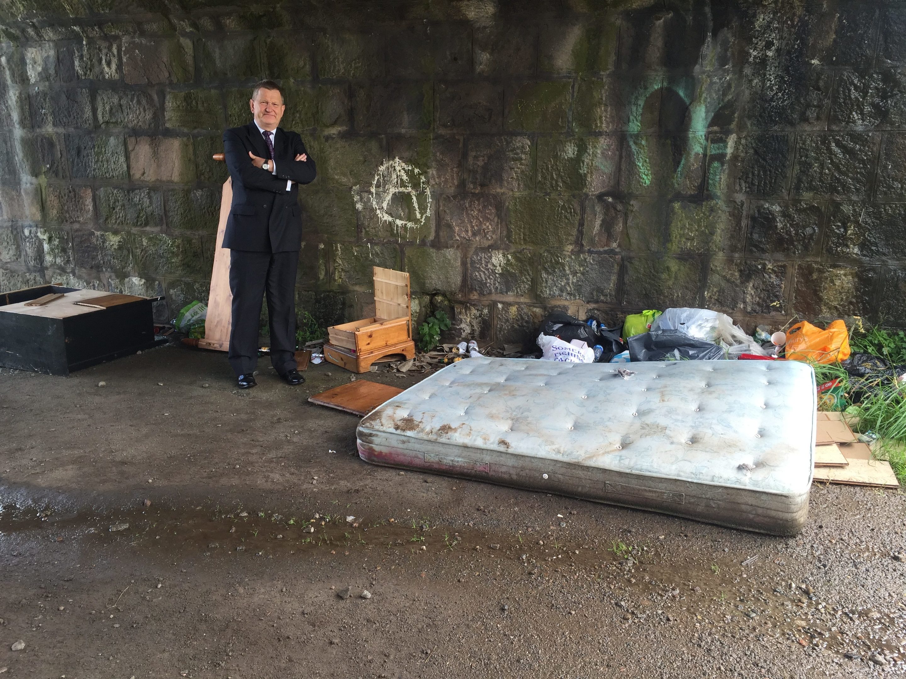 Councillor Alex Nicoll with garbage dumped by fly-tippers on Coast Road.