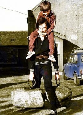 Jim Spaine Snr lifts the Dinnie Steens with son Jim jnr on his back in 1975 at the Potarch Hotel.