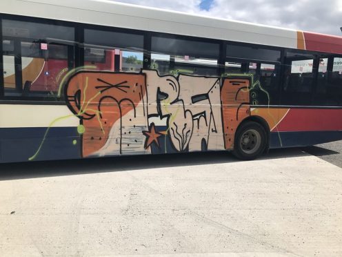 The graffiti was sprayed on the side of the Stagecoach bus while it was parked near a cemetery