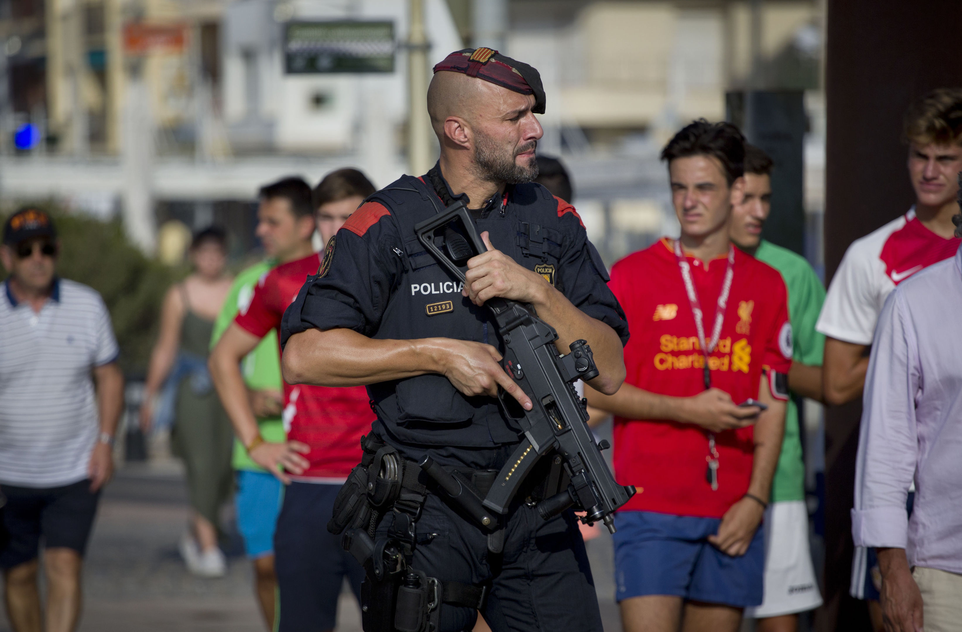 An armed policeman grimaces while on patrol in Cambrils, Spain, Friday, Aug. 18, 2017. Spanish police on Friday shot and killed five people carrying bomb belts who were connected to the Barcelona van attack that killed at least 13, as the manhunt intensified for the perpetrators of Europe's latest rampage claimed by the Islamic State group. (AP Photo/Emilio Morenatti)