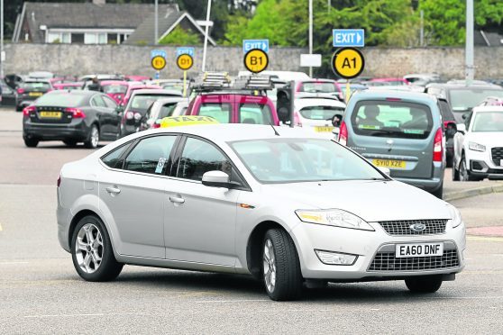A taxi at Raigmore Hospital with busy car park in the background