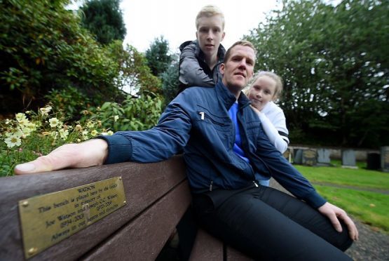 Fraser (seated) with his son Joe and daughter Amy on the Joe Watson bench in the graveyard.
