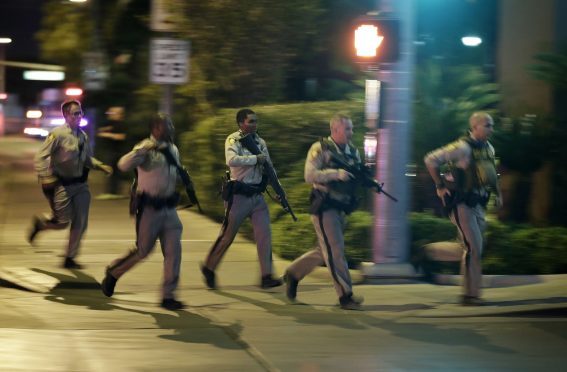 Police run to cover at the scene of a shooting near the Mandalay Bay resort and casino on the Las Vegas Strip