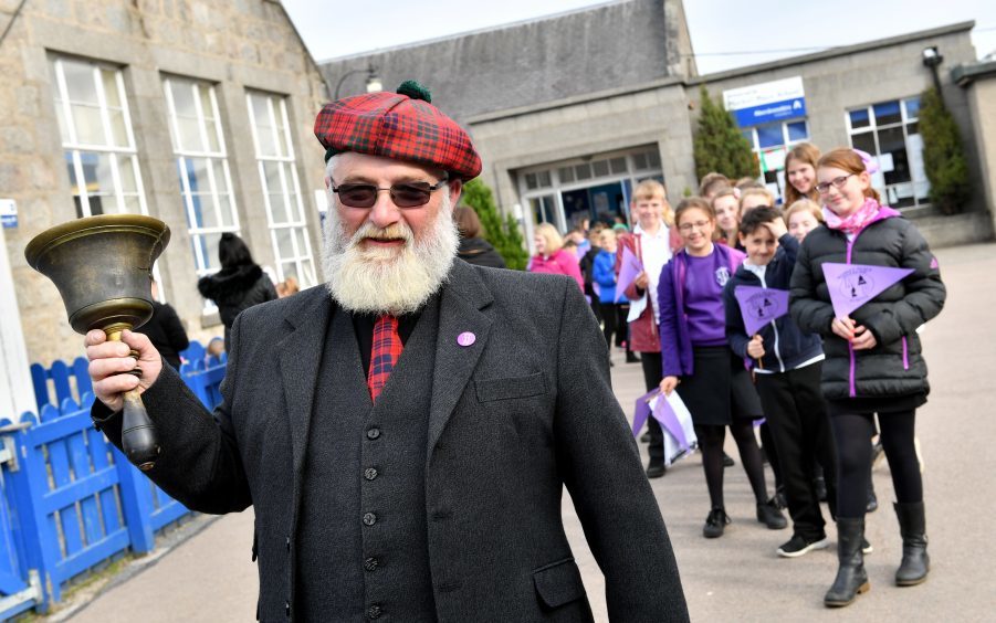 Janitor Michael Ross who rang the school bell for the last time leads the pupils out to Market Square.