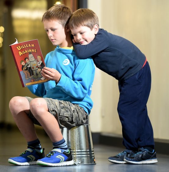 Alasdair Stiubhart enjoys a newly released Oor Willie book which has been translated in to Gaelic. Also in the photograph is younger brother Seumas.