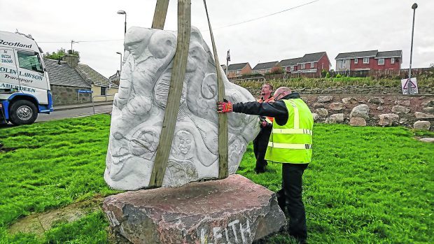 Pictures of the Isie Caie fisherwoman statue at Cove Harbour being lowered into place.