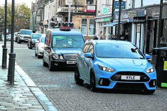 A car with Kyle's name on the name plate leads the hearse followed by 70 cars through Fort William high street