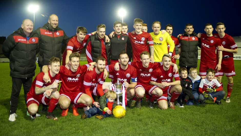 The Brora team celebrate with the cup.