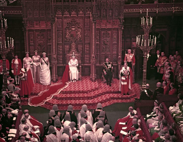 Queen Elizabeth II, watched by the Duke of Edinburgh, reads her speech from the Throne in the House of Lords chamber at the State Opening of Parliament. October 1958.
