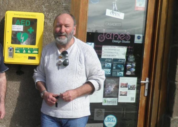 Phil Mills-Bishop pictured next to the harbour defibrillator shortly after its installation