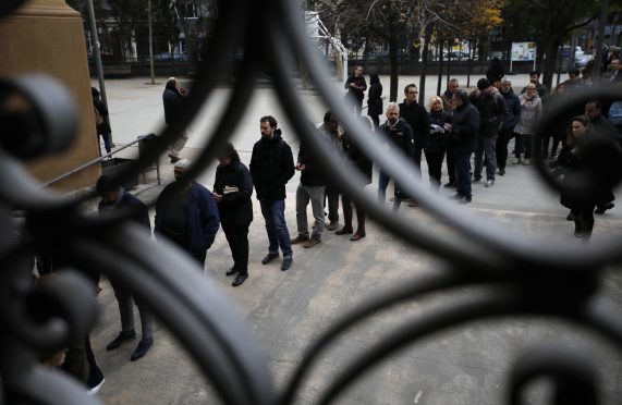 People line up outside a polling station to cast their vote for the Catalan regional election in Barcelona, Spain.