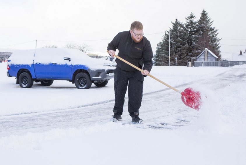 A worker at Dalwhinnie clears snow from around the distillery.