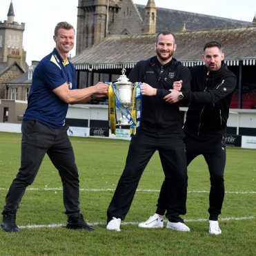 Rangers legend Arthur Numan wrestles Fraserburgh's Ryan Christie and Marc Dickson for the cup.