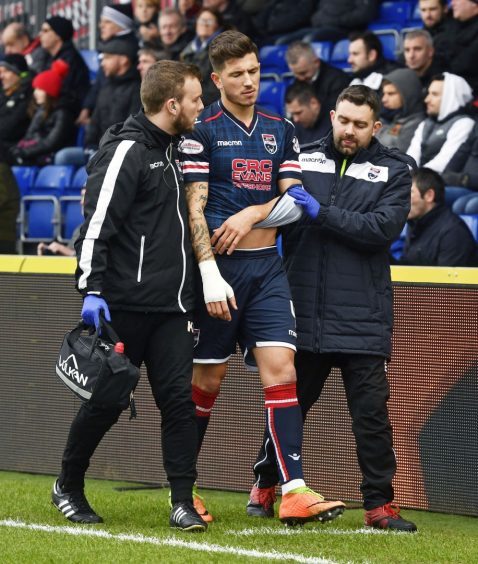 Ross County's Christopher Routis leaves the field with an injury.