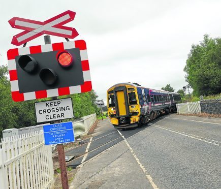 A southbound train crosses the Lairg automatic open level crossing