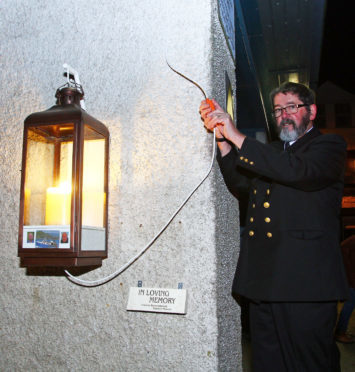 Matthew Ramsay, superintendent of the Fishermen's Mission performs the switching on of the candle at the vigil held on the quay in Tarbert.  Picture: Kevin McGlynn