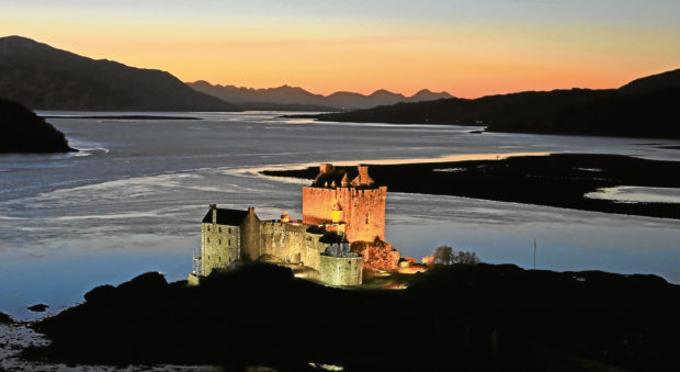 The historic floodlit Eilean Donan Castle with the sun setting behind the Cuillin mountain range on the Isle of Skye.. .. (c) Stephen Lawson | Edinburgh Elite media