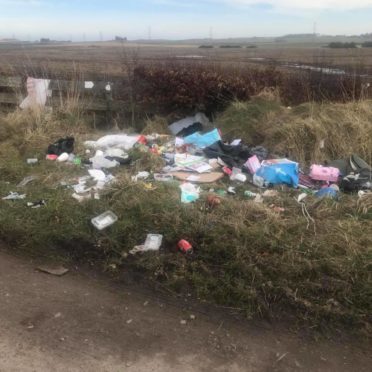 Piles of waste including food wrappers, cardboard boxes and black bags, have been left strewn near a track at Blackhills outside Peterhead.