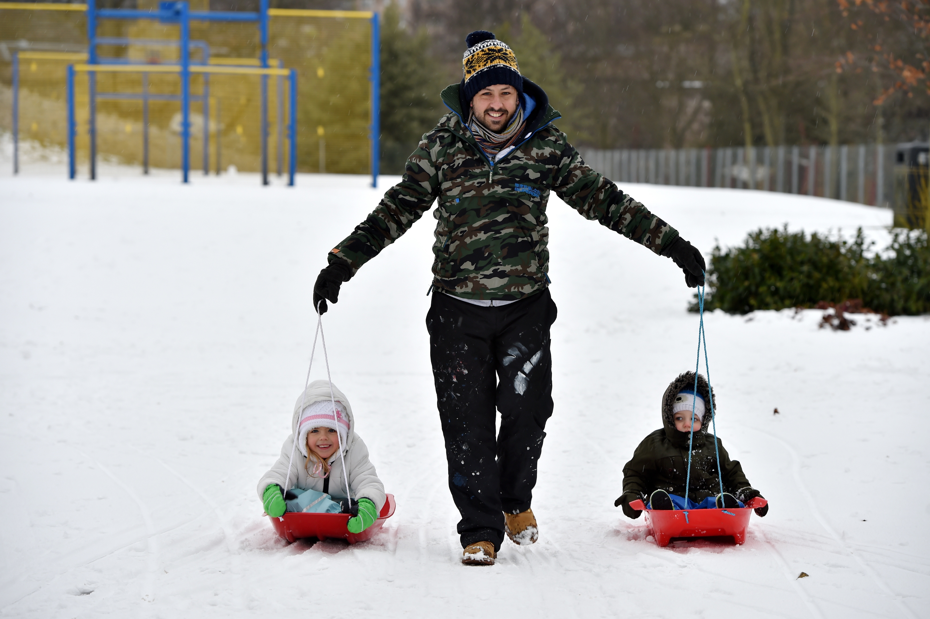 Colin Milne pulling Ella-Marie, 5, and Lachlan, 2, in sledges, at Duthie Park.
