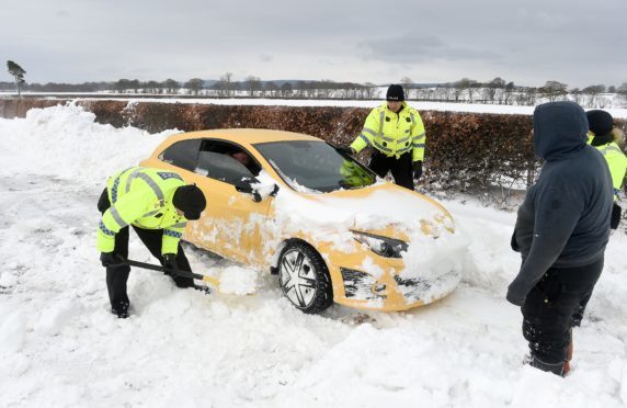 Police and farmers with heavy machinery recover cars and clear deep drifts on the road between Arabella and Hill of Fearn in Easter Ross yesterday morning.
Picture by Sandy McCook.