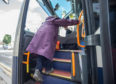 A passenger climbs the bus after boarding in Forres