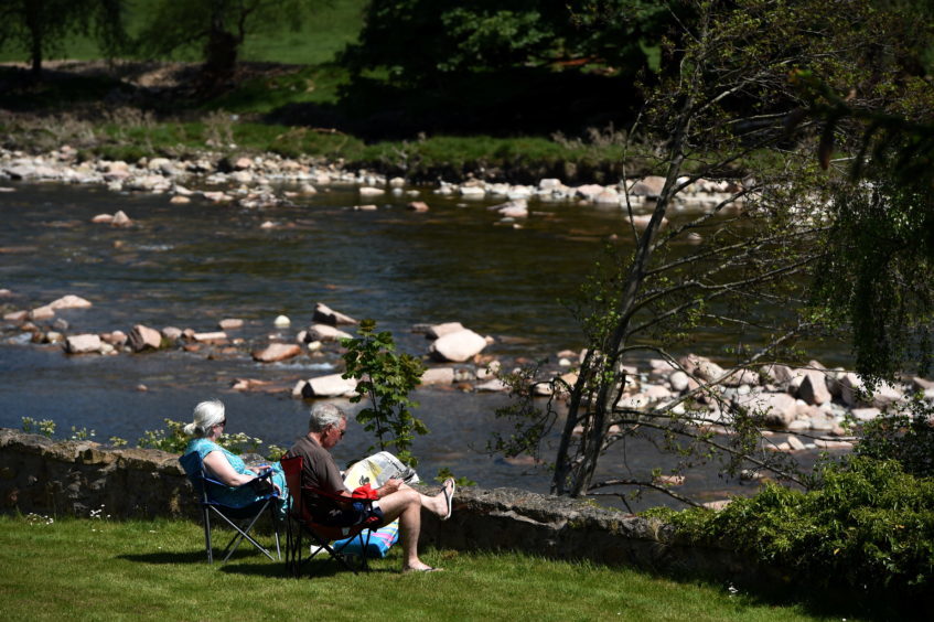 Tourists enjoying the sun on the banks of the River Dee