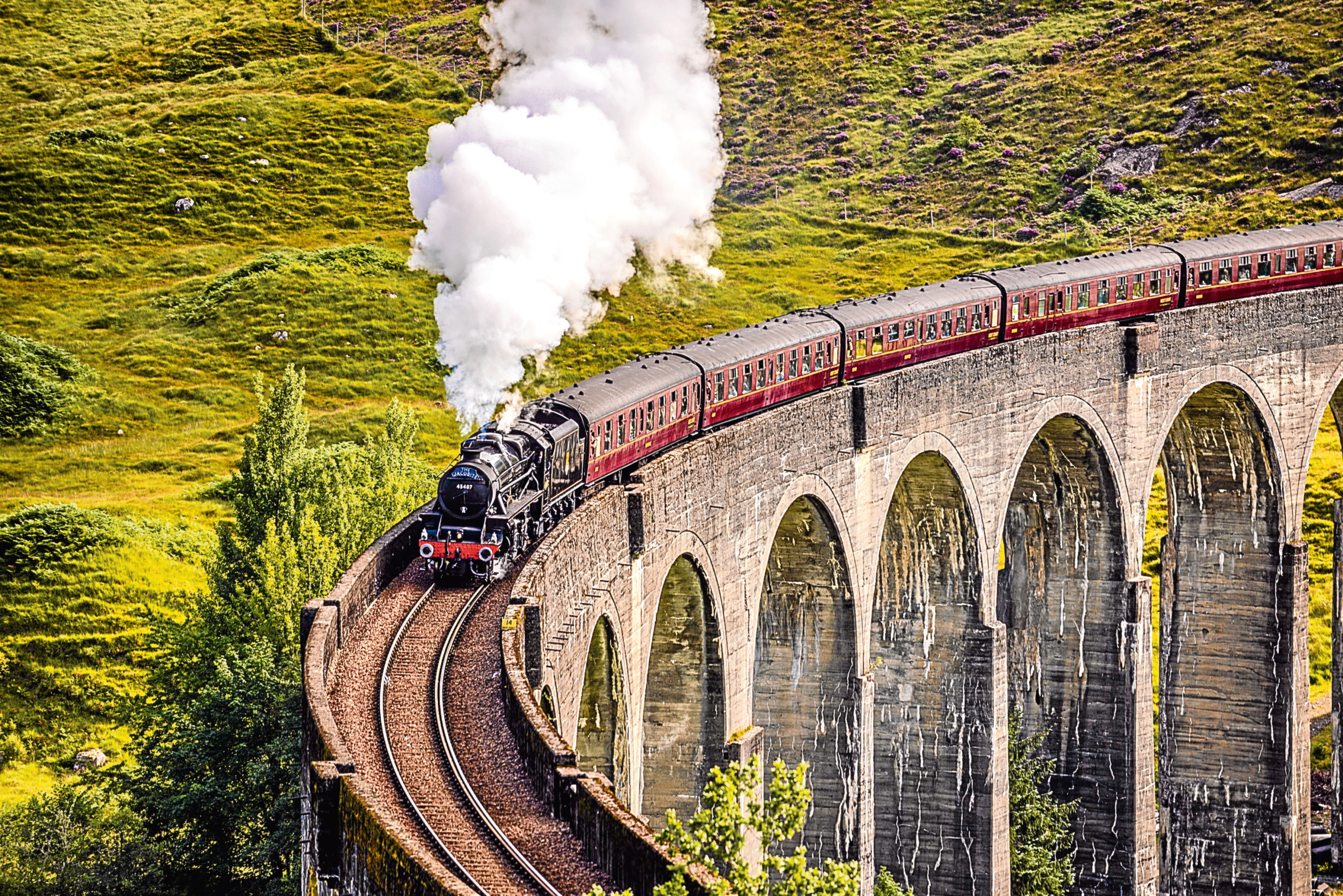 Glenfinnan Railway Viaduct in Scotland with the Jacobite steam train passing over.