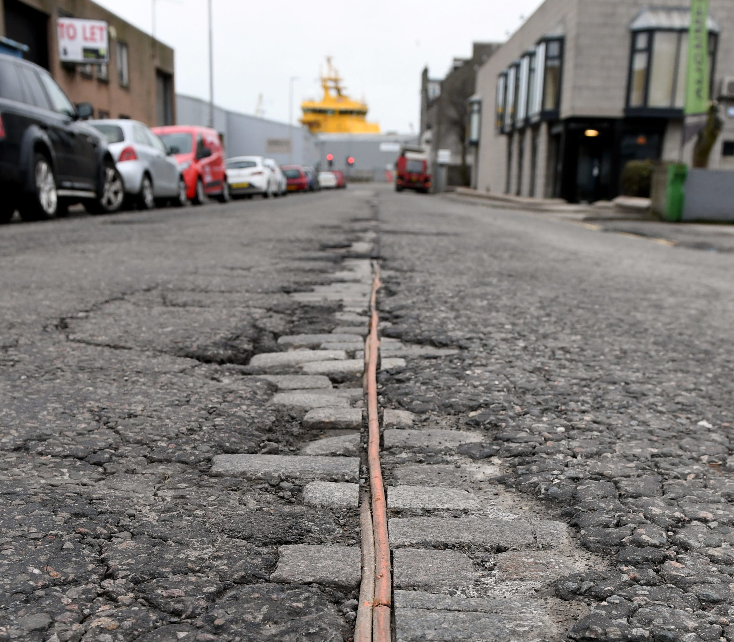 The tarmac has broken up on Commerce Street, Aberdeen, revealing the old cobbles and cables underneath.