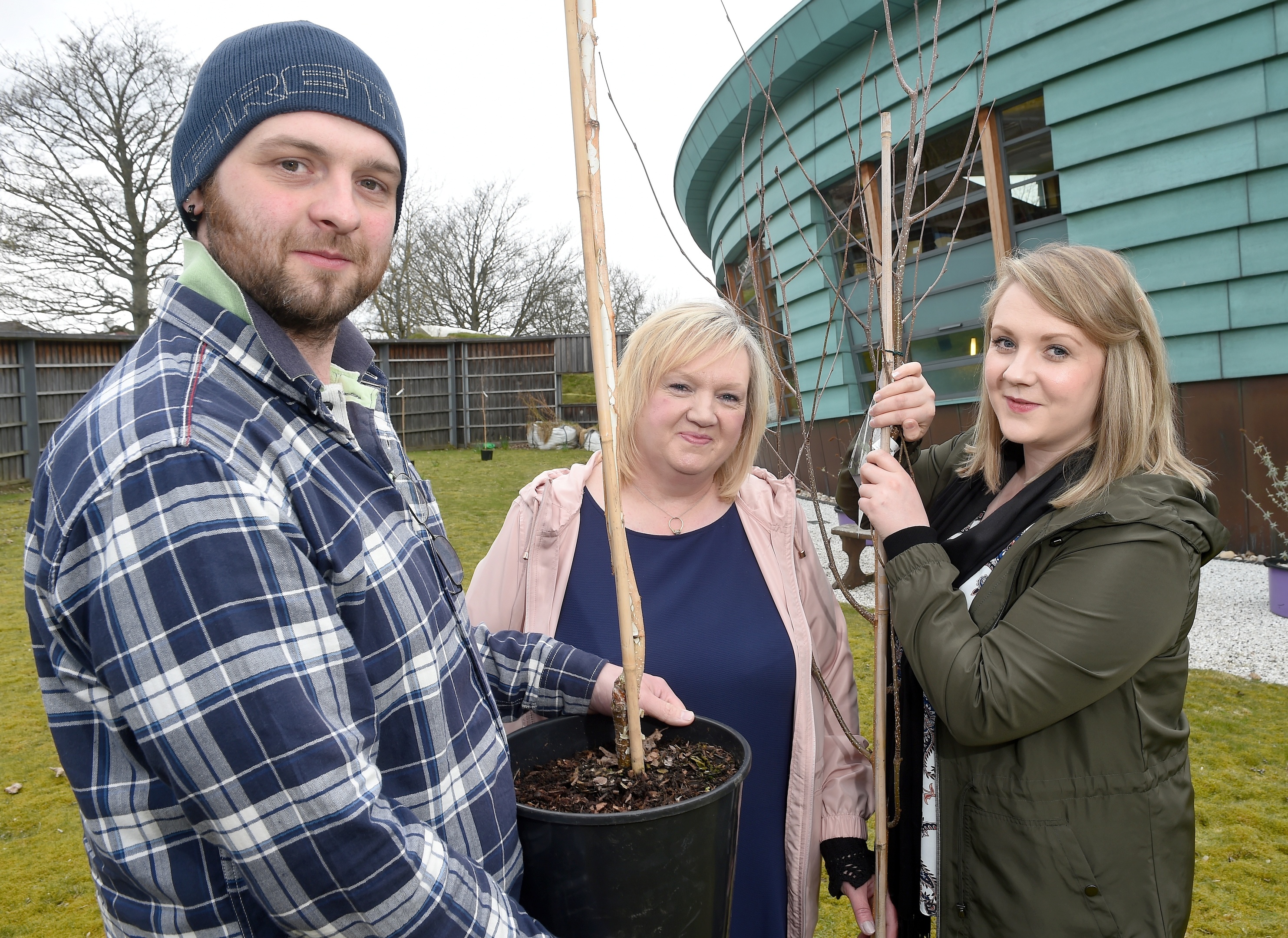 Lynda Fraser (centre) with her son Conrad and daughter Samantha help family members plant seven commemorative trees in the grounds of Maggie's Highland in Inverness in memory of her husband and their father Stuart who died in December.