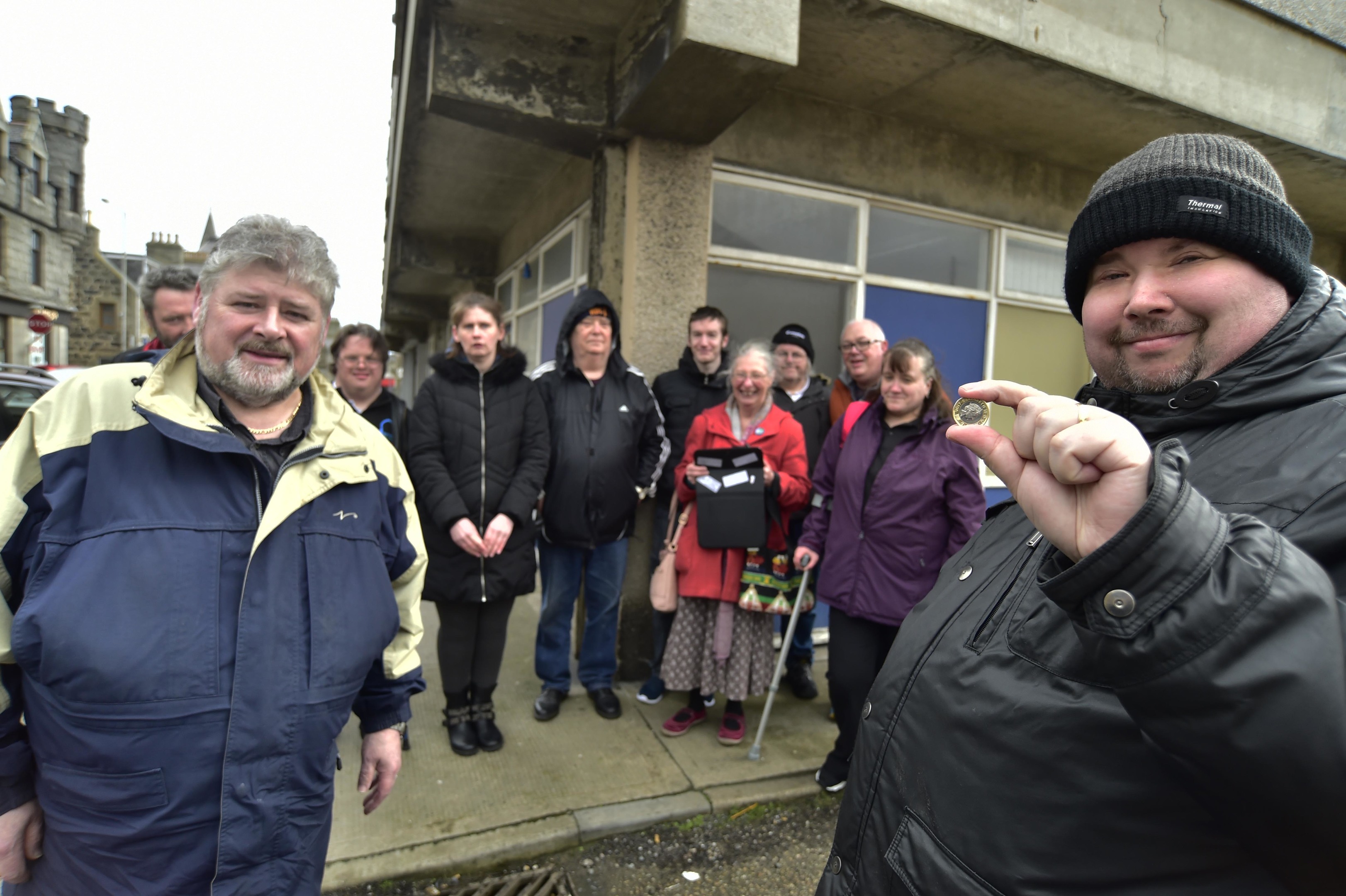 People First Chairman Fraser Haldane shows a £1 coin to facilitator Stewart Whyte and group members which was what the group paid to Aberdeenshire Council for the former offices in Mid Street.