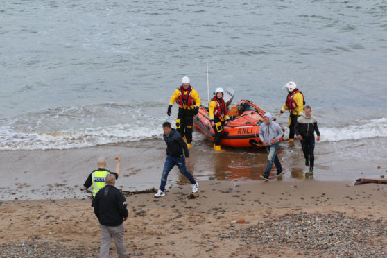 The three men were brought ashore to the beach where they were met by police.