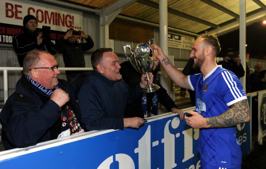 Jonathan Smith shows the trophy to Cove supporters.