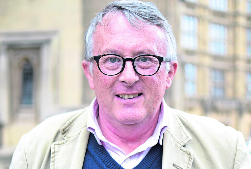 Caithness, Sutherland and Ross MP Jamie Stone smiling at the camera, wearing a tan coat, and dark glasses. 