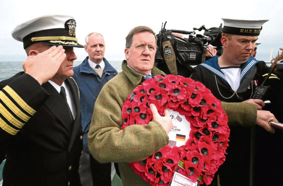 Lord George Robertson holds a wreath prior to throwing it in the sea close to the wreck of SS Tuscania which sank in 1918 off the coast of Islay.