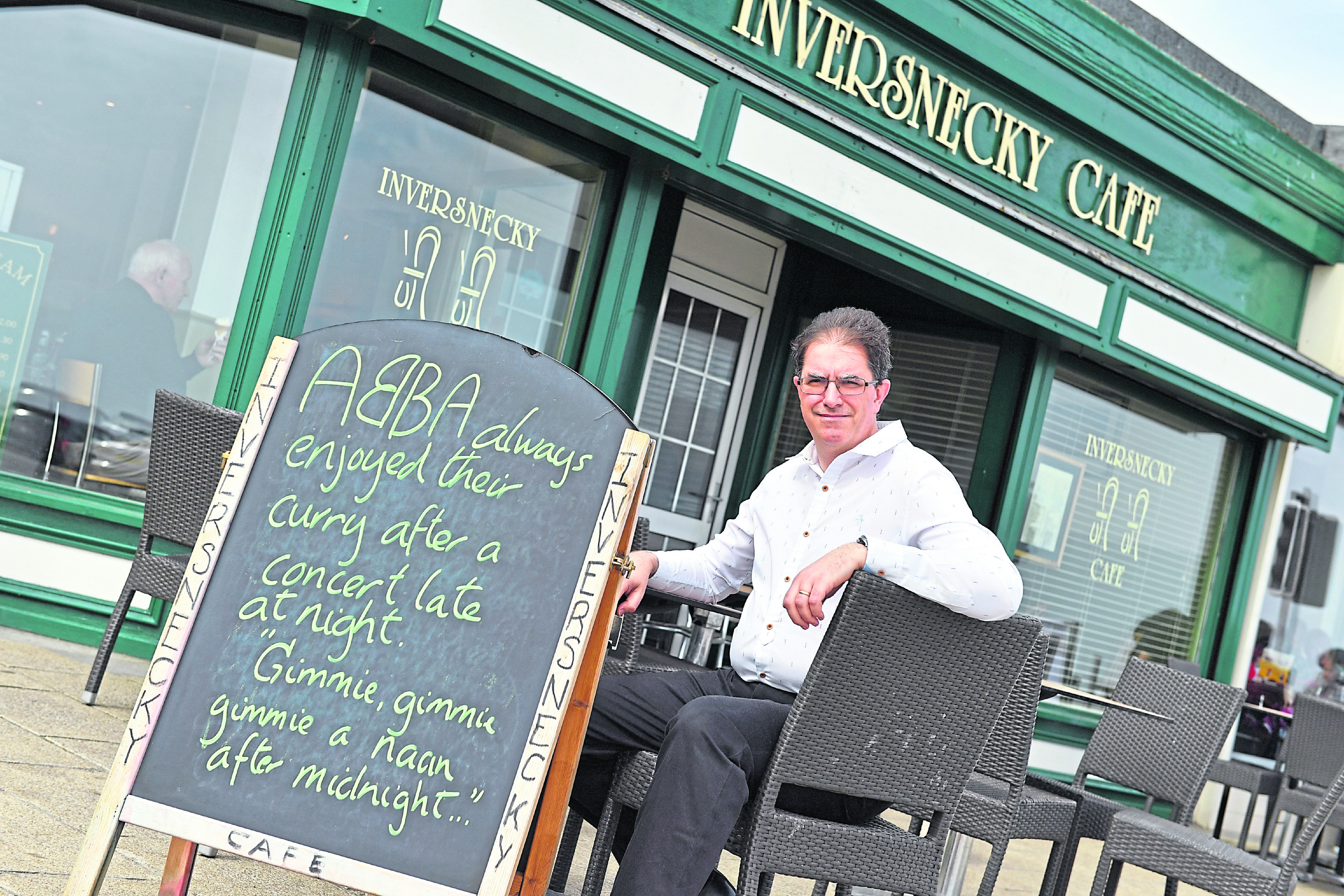 Martin Vicca outside the Inversnecky Cafe at Aberdeen Beach with some of the witty boards. Photograph by Kami Thomson