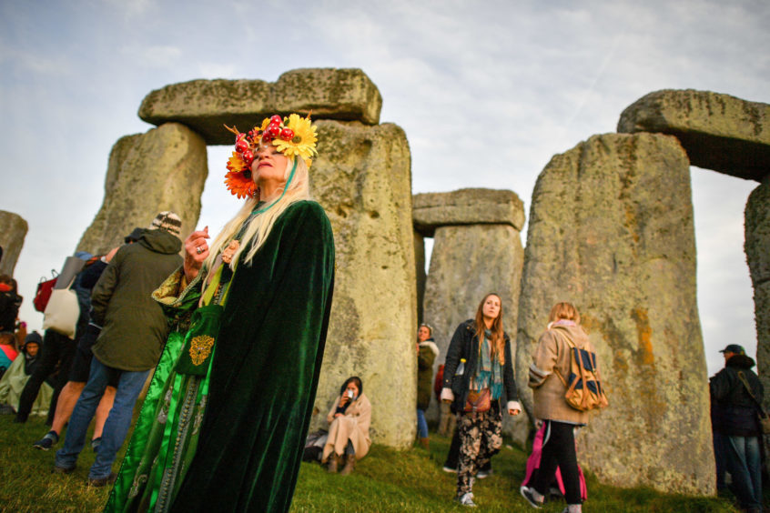 A woman wears a colourful head-dress at Stonehenge. Photo: Ben Birchall/PA Wire