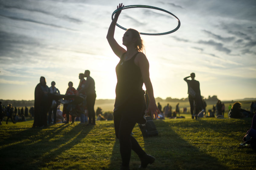 A woman twirls a hula-hoop as the sun rises at Stonehenge. Picture: Ben Birchall/PA Wire