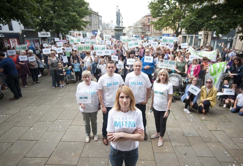 Hundreds of Keep Mum protesters, many wearing white t-shirts and holding placards. Spokeswoman Kirsty Watson stands in the front with her arms folded. 