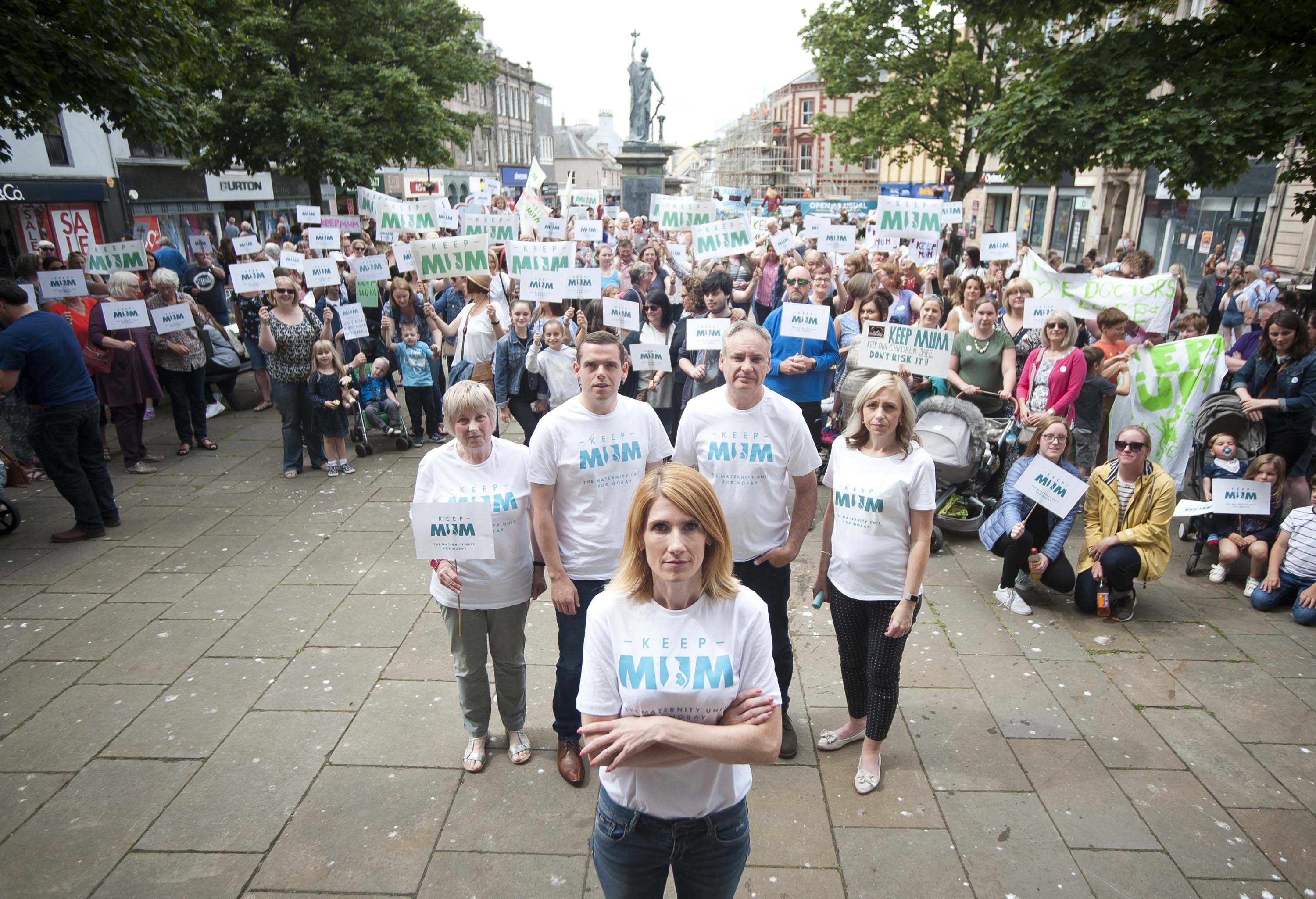 Hundreds of Keep Mum protesters, many wearing white t-shirts and holding placards. Spokeswoman Kirsty Watson stands in the front with her arms folded.